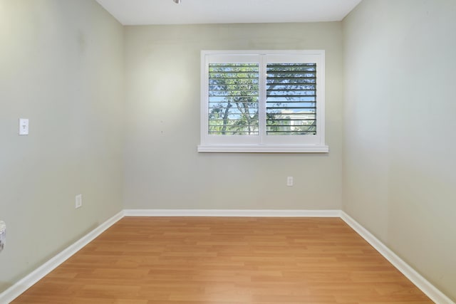 spare room featuring baseboards and light wood finished floors