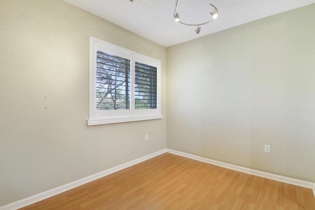 spare room featuring a textured ceiling, wood finished floors, and baseboards