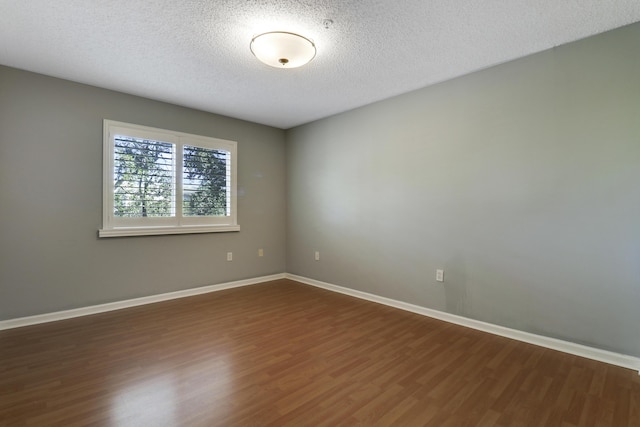 empty room with a textured ceiling, baseboards, and dark wood-style flooring