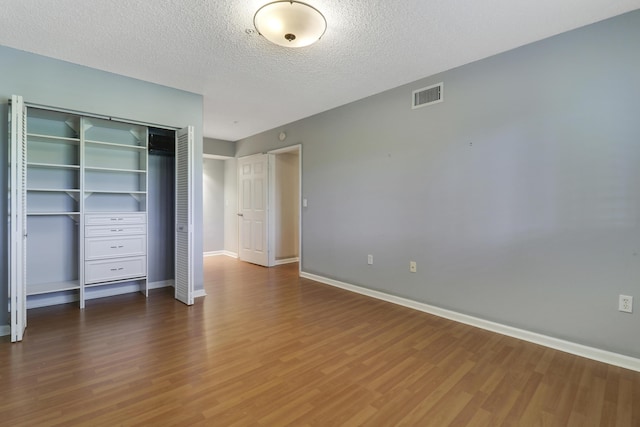 unfurnished bedroom with baseboards, a closet, visible vents, and wood finished floors