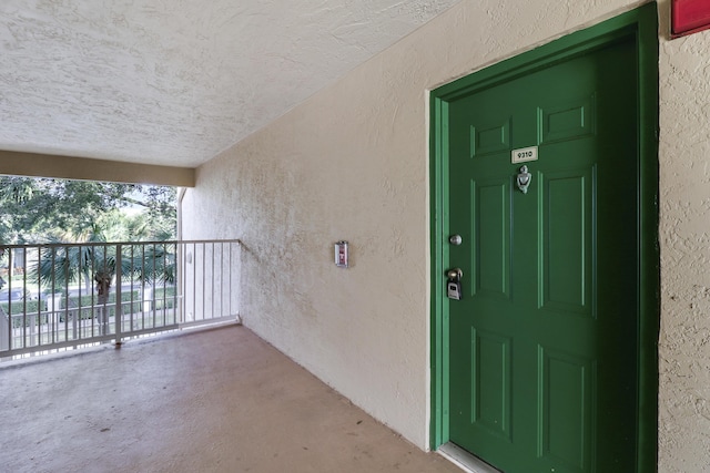 property entrance with a balcony and stucco siding