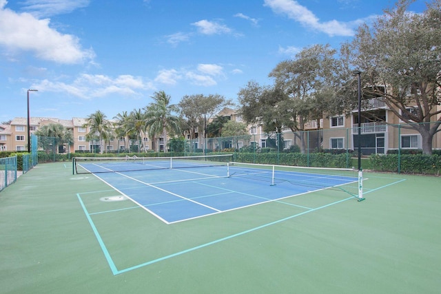 view of tennis court with fence and a residential view