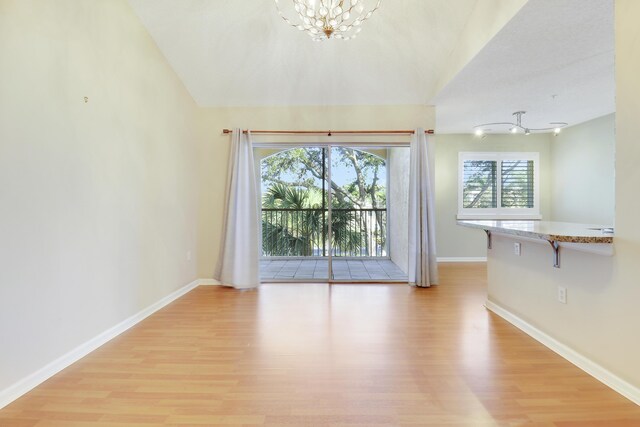 interior space with vaulted ceiling, an inviting chandelier, wood finished floors, and baseboards