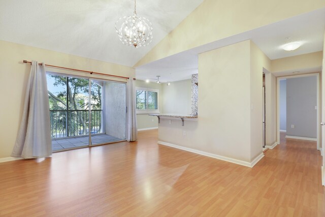 unfurnished room with light wood finished floors, baseboards, vaulted ceiling, and a notable chandelier