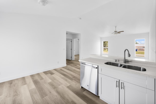 kitchen featuring a sink, white cabinetry, vaulted ceiling, stainless steel dishwasher, and light wood-type flooring