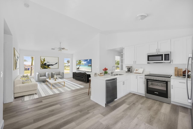 kitchen with stainless steel appliances, white cabinetry, a sink, and a peninsula