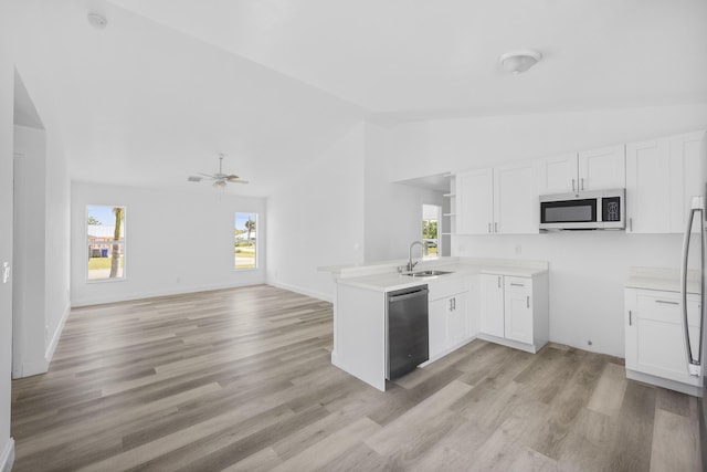 kitchen featuring a peninsula, a sink, white cabinetry, open floor plan, and appliances with stainless steel finishes