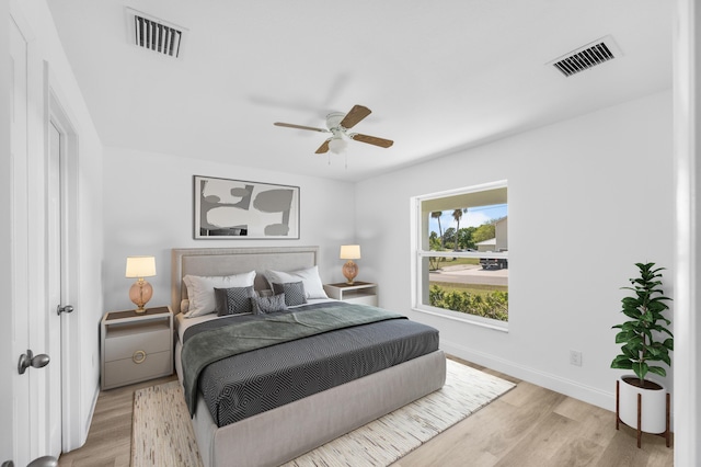 bedroom with light wood finished floors, visible vents, and baseboards