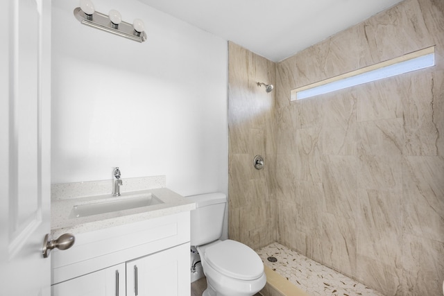 full bathroom with tiled shower, vanity, and toilet