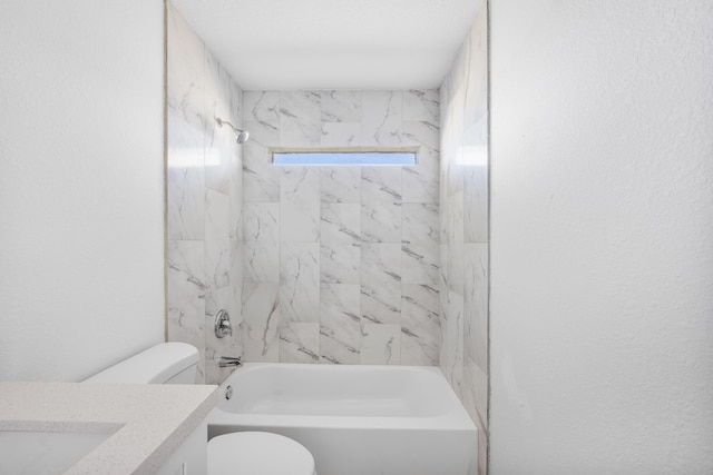 bathroom featuring a textured wall, shower / washtub combination, vanity, and toilet