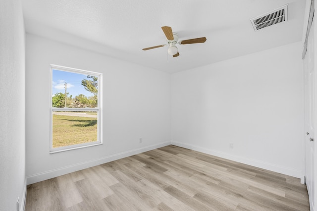 spare room with light wood finished floors, baseboards, visible vents, and ceiling fan