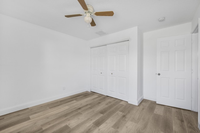 unfurnished bedroom with baseboards, a closet, visible vents, and wood finished floors