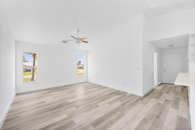 spare room with lofted ceiling, light wood-style floors, and baseboards