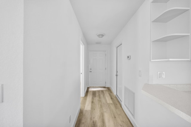 corridor with visible vents, light wood-style flooring, and baseboards