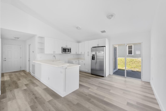 kitchen featuring appliances with stainless steel finishes, white cabinetry, a peninsula, and open shelves