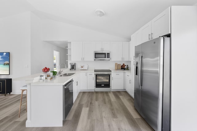 kitchen with a peninsula, a sink, white cabinets, appliances with stainless steel finishes, and open shelves