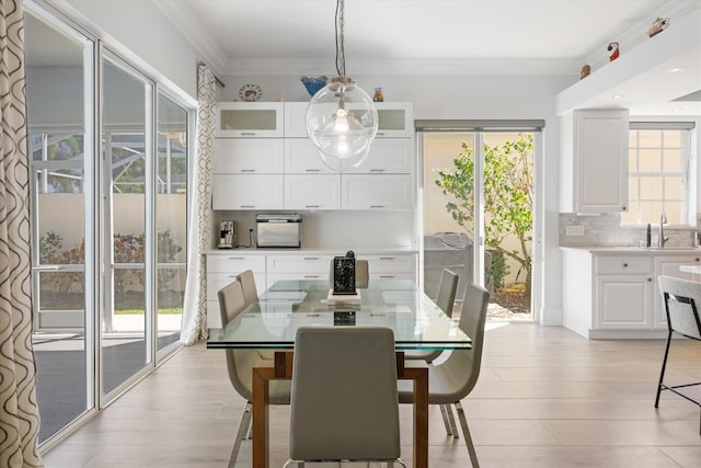 dining area with light wood-style flooring and crown molding