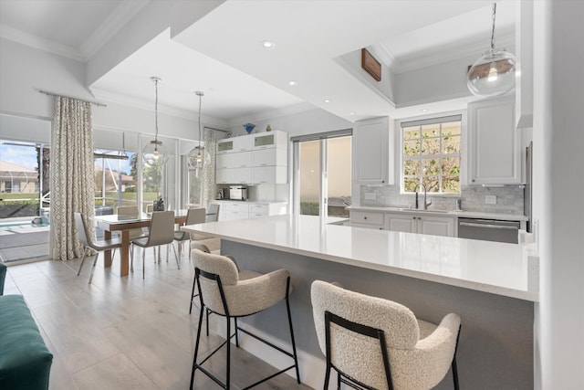 kitchen with crown molding, decorative backsplash, a kitchen breakfast bar, stainless steel dishwasher, and a sink