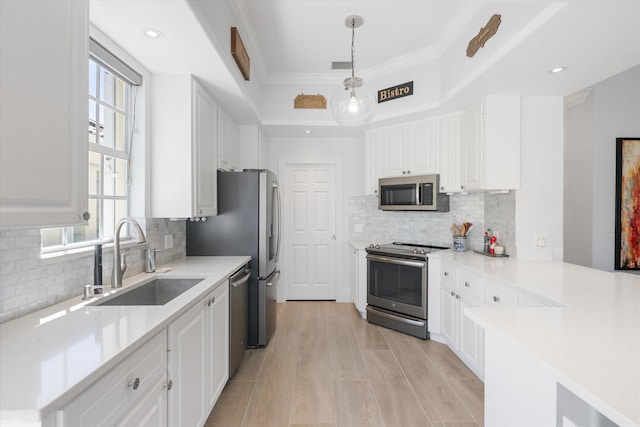 kitchen with a sink, appliances with stainless steel finishes, white cabinets, light countertops, and a raised ceiling