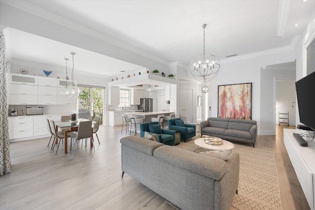 living area featuring a notable chandelier, light wood-style flooring, and crown molding