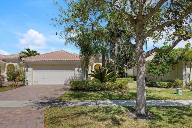 view of front of property featuring stucco siding, a front lawn, decorative driveway, an attached garage, and a tiled roof