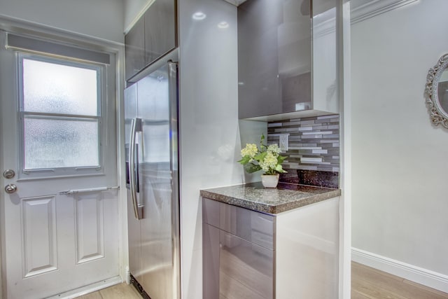 interior space featuring stainless steel dishwasher, dark stone counters, stove, decorative backsplash, and modern cabinets