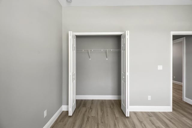 unfurnished bedroom featuring a closet, baseboards, and wood finished floors