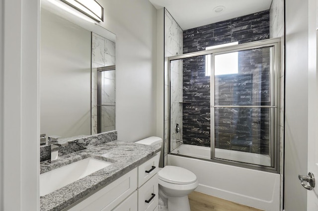 full bathroom featuring vanity, toilet, wood finished floors, and enclosed tub / shower combo