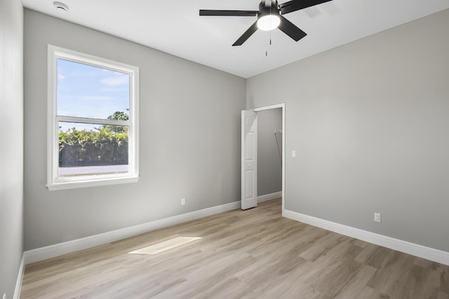 unfurnished room with baseboards, light wood-style floors, and a ceiling fan