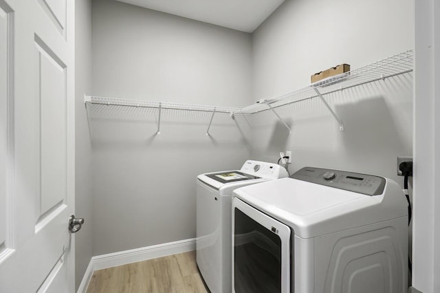 laundry area featuring washer and clothes dryer, laundry area, baseboards, and light wood-style floors