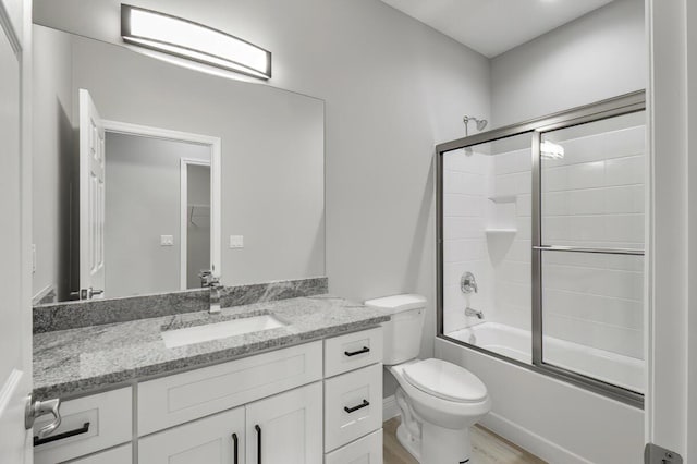 bathroom featuring vanity, toilet, wood finished floors, and combined bath / shower with glass door