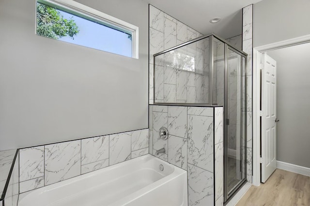 bathroom with a stall shower, baseboards, a garden tub, and wood finished floors