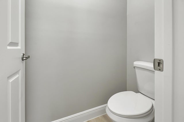 bathroom with toilet, wood finished floors, and baseboards