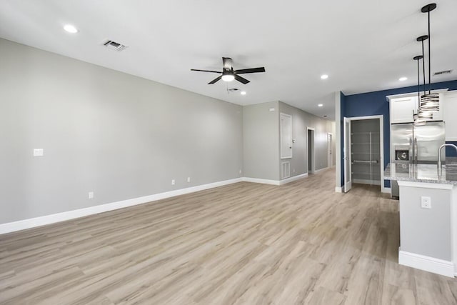 unfurnished living room with visible vents, a ceiling fan, recessed lighting, light wood-style floors, and baseboards