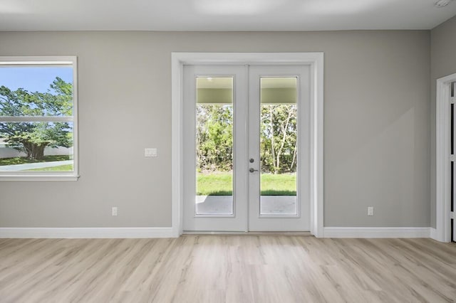 doorway with french doors, baseboards, and light wood finished floors