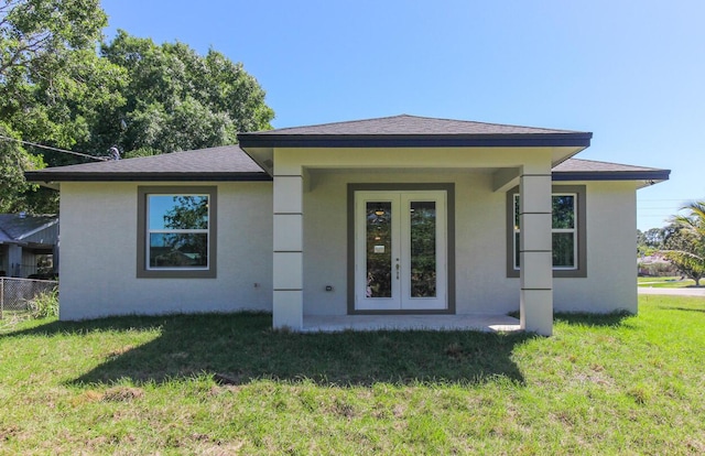 back of house featuring a lawn, french doors, and stucco siding