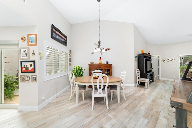 dining space with light wood-style floors, a notable chandelier, vaulted ceiling, and baseboards