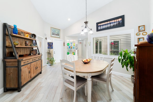 dining area with high vaulted ceiling, light wood-style flooring, and baseboards