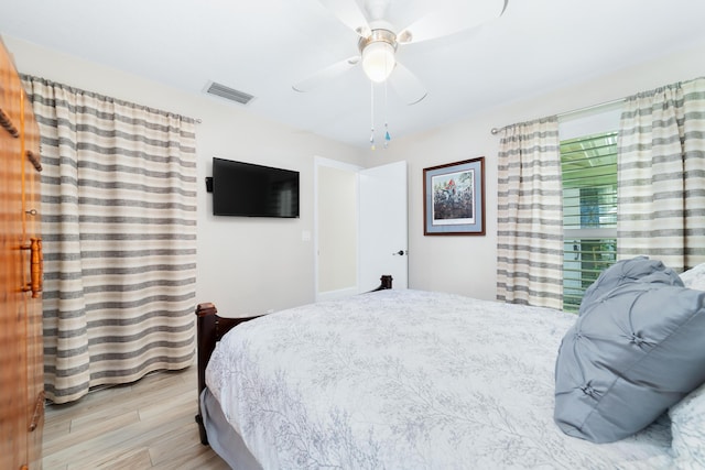 bedroom with a ceiling fan, visible vents, and wood finished floors