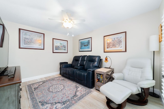 living area with light wood-type flooring, ceiling fan, and baseboards