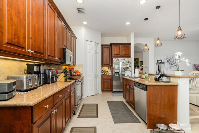 kitchen featuring a sink, visible vents, appliances with stainless steel finishes, decorative backsplash, and light stone countertops