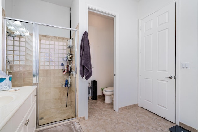 bathroom with toilet, a shower stall, vanity, baseboards, and tile patterned floors