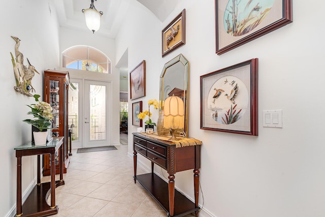 entrance foyer featuring french doors, light tile patterned flooring, a towering ceiling, and baseboards