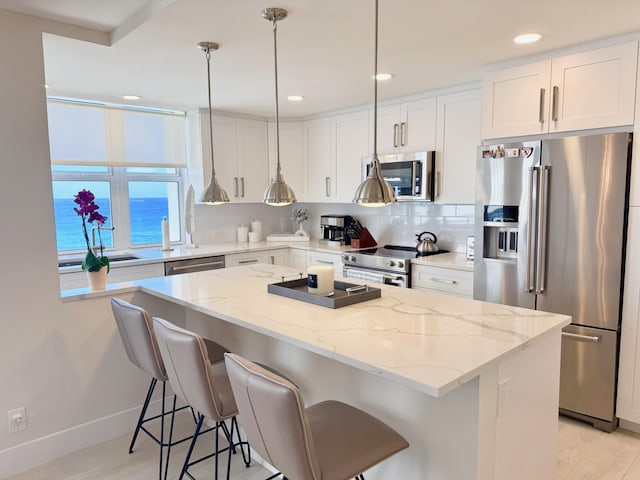 kitchen featuring a breakfast bar, light stone countertops, appliances with stainless steel finishes, and decorative backsplash