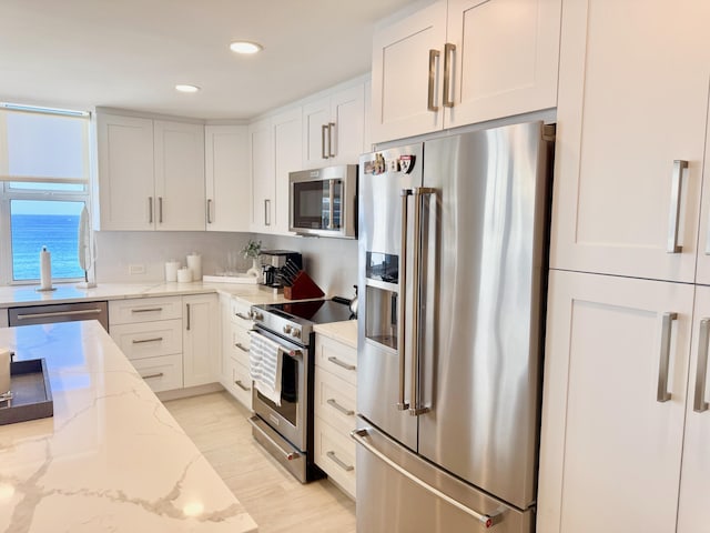 kitchen featuring stainless steel appliances, recessed lighting, light wood-style floors, white cabinetry, and light stone countertops