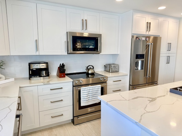 kitchen with white cabinets, light stone counters, stainless steel appliances, backsplash, and recessed lighting