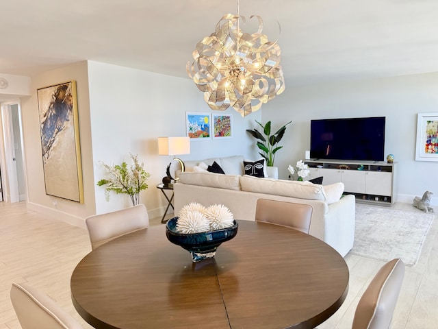 dining space with baseboards, wood finished floors, and a notable chandelier