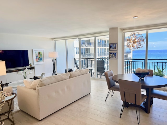 living area with a chandelier, a healthy amount of sunlight, floor to ceiling windows, and a water view