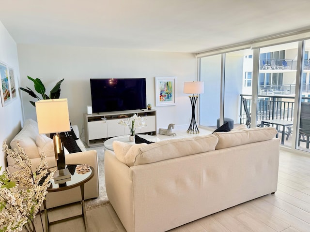 living area with a wall of windows and light wood-style flooring