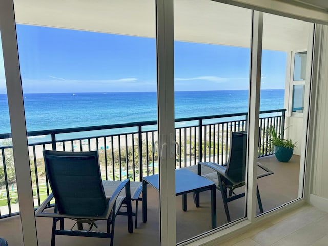 balcony with a water view and a view of the beach